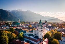 Stredoveké mesto Hall in Tirol s vežami, domami a horami v pozadí.