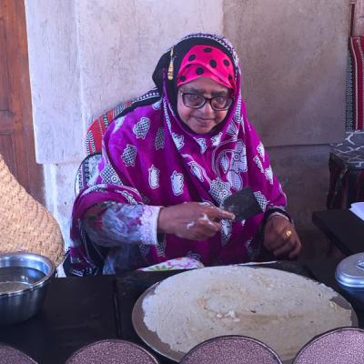 Tradične oblečená žena pečie chlieb. Omán