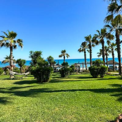 Záhrada, palmy a more v diaľke pred hotelom Turan Prince. Turecko