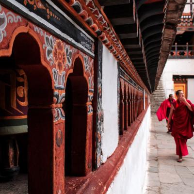 Drevený chrám s výzdobou a traja mnísi. Bhután.