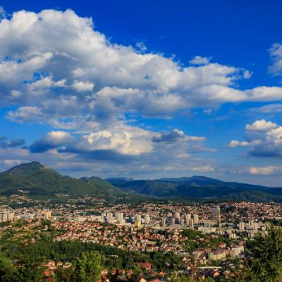 Panoramatický pohľad na mesto obklopené zelenými kopcami.