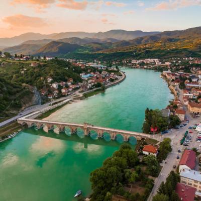 Rieka v meste, most, zelené kopce a domy.