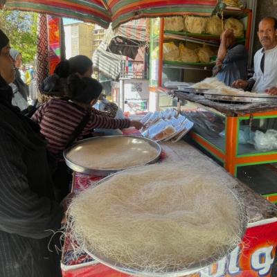 Kunafové cesto a predávajúci a kupujúce ženy na trhu v Egypte.