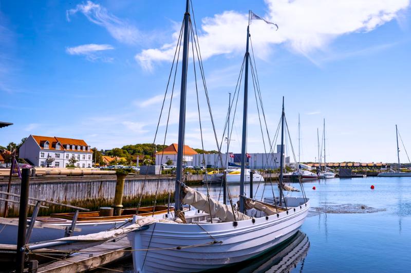 Loď v prístave a domy počas slnečného dňa. Ebeltoft. Dánsko. Foto: unsplash.com