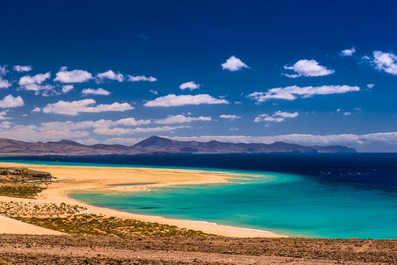 Piesková pláž, tyrkysový oceán a sopečné pohorie. Fuerteventura. Foto: unsplash.com