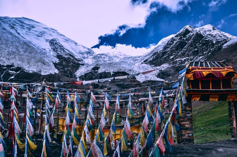 Zasnežené Himaláje, farebné vlajky a brána. Čína. Foto: unsplash.com