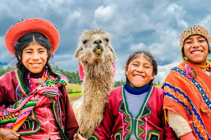 Deti pestro oblečené do ponča a lama. Pisac. Peru. Foto: unsplash.com