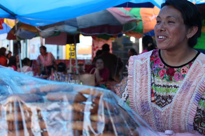 Guatemalská žená vo farebnom kroji ponúka pečivo. Quetzaltenango. Foto: unsplash.com