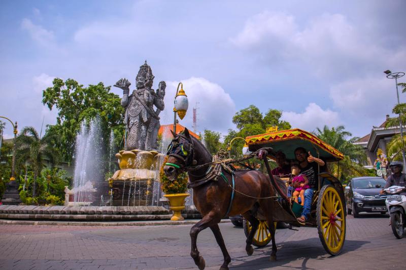 Denpasar a centrum mesta so sochou v centre, kôň a koč s ľudmi. Foto: unsplash.com