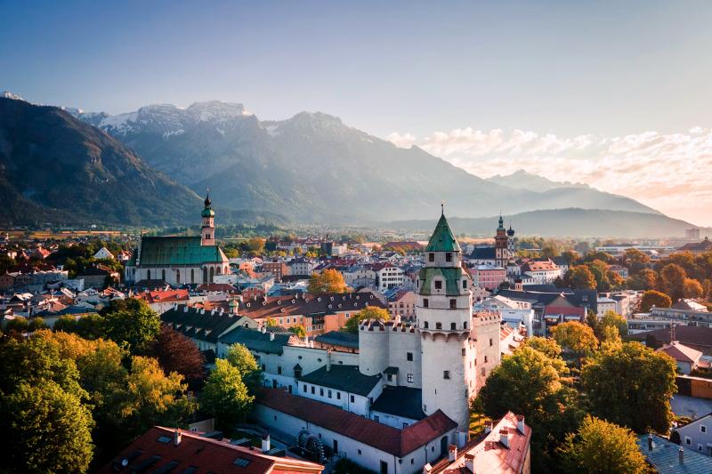 Stredoveké mesto Hall in Tirol s vežami, domami a horami v pozadí.