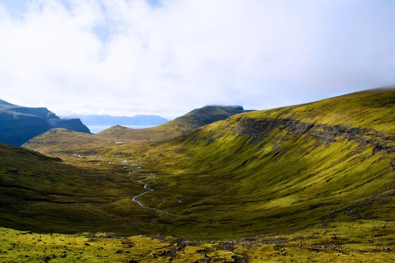 Zelené údolie, rieka, kopce a more v pozadí ostrova Streymoy, Faerské ostrovy. Foto: unsplash.com