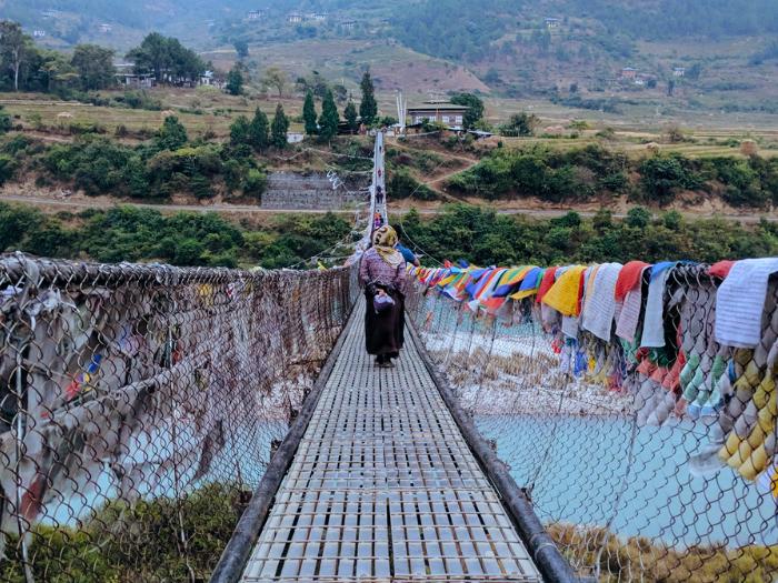 Visutý most Punakha a kráčajúca žena. Bhután