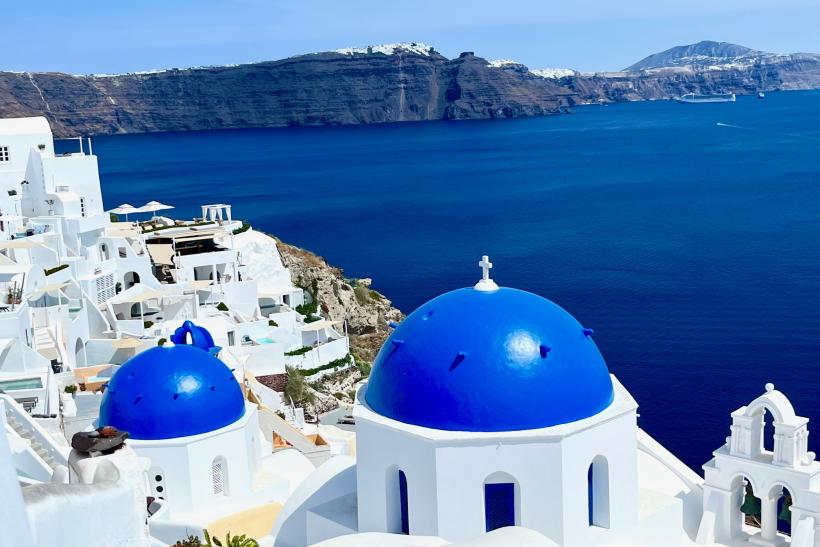 Modré kupoly a biele domčky, výhľad na mesto Oia a sopečný ostrov Santorini. Grécko.