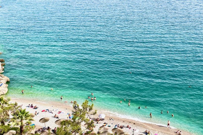 Kemienková pláž v Nafpliu a ľudia vo vode a na pláži.