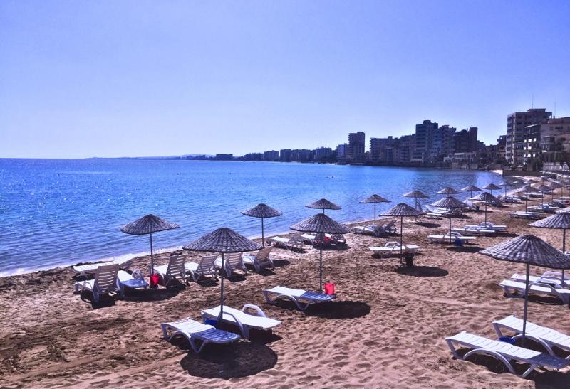 Varosha - piesočnatá pláž s lehátkami a okolité hotely.