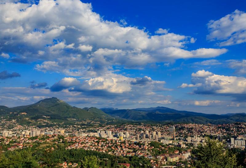 Panoramatický pohľad na mesto obklopené zelenými kopcami.