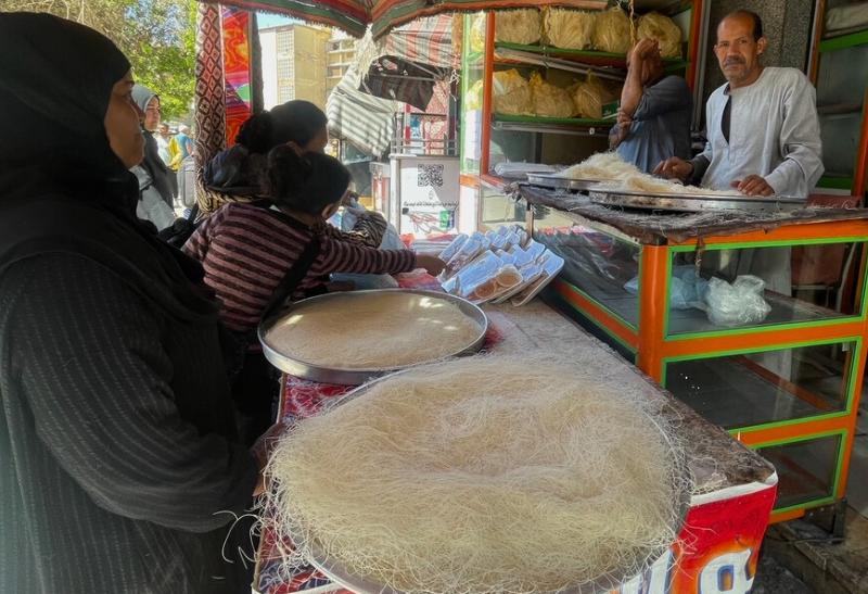 Kunafové cesto a predávajúci a kupujúce ženy na trhu v Egypte.