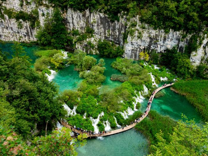 Plitvické jazerá a drevený chodník a kráčajúci turisti. Chorvátsko.